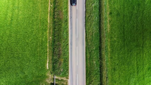 Top-down drone view of a rural country road through green fields