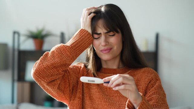 Video of sick woman holding a thermometer showing she has a fever while at home  