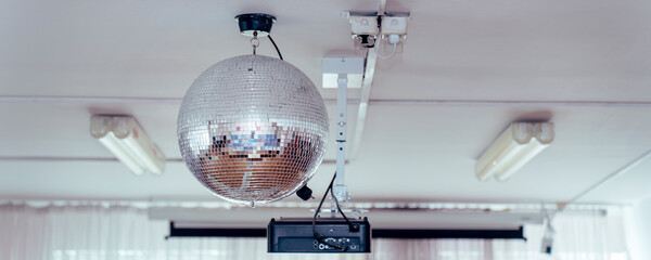 Disco ball reflecting light, hanging next to a projector in a modern room, ready for entertainment...