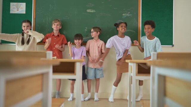 Diverse group of school children enjoying dance activity with teacher in an international classroom, encouraging active learning and teamwork