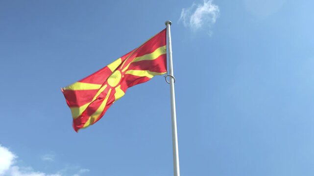 North Macedonia flag waving on pole against blue sky sunny day