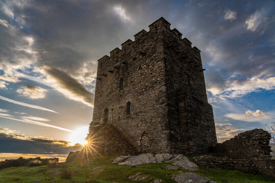 Dolwyddelan Castle tower rising against a dramatic morning sky with sunstar at dawn