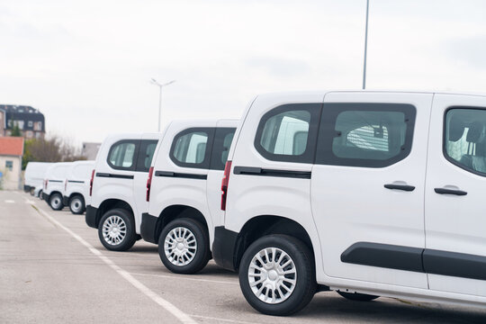 White delivery vans are parked in rows. Commercial fleet of vehicles