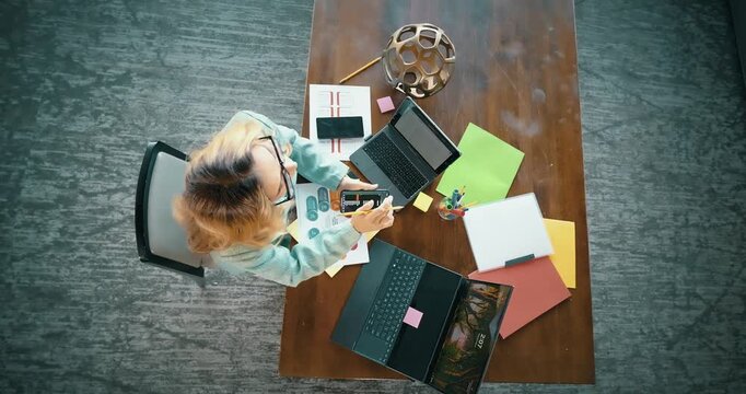 Overhead View of Woman Working with Laptops and Documents