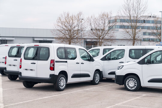 White delivery vans are parked in rows. Commercial fleet of vehicles