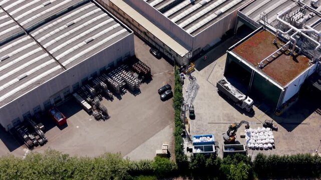 Aerial View of Industrial Warehouse Complex: An expansive industrial complex featuring large warehouses, loading docks, trucks, and various machinery.