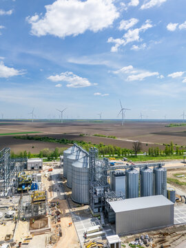 Construction of a modern agricultural grain terminal with wind turbines on the horizon