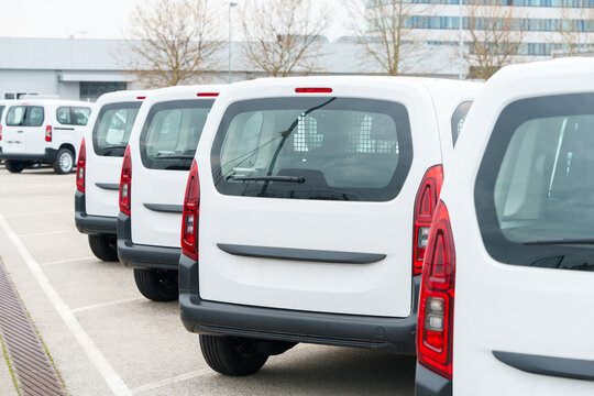 White delivery vans are parked in rows. Commercial fleet of vehicles