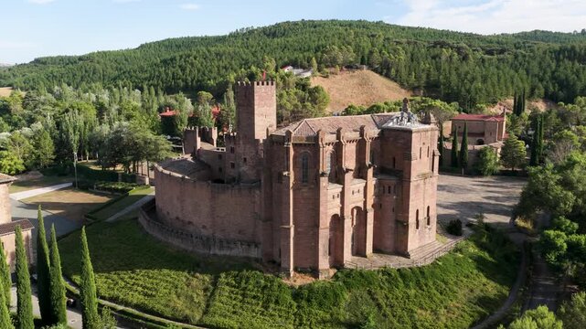 Breathtaking aerial footage orbiting the historic castle of javier in navarre, spain. The medieval fortress stands on a hill surrounded by lush green forests