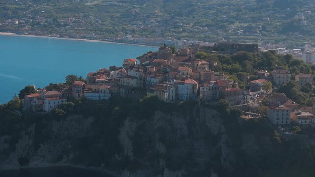 Slow orbit right aerial drone shot of Agropoli, Campania, Italy, showing the harbor, historic center and Mediterranean coastline at sunset with smooth cinematic motion