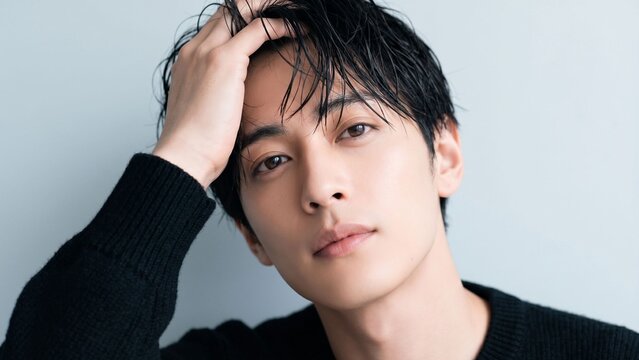 濡れた前髪に手を添えながら静かな視線を向ける若い男性のメンズビューティーポートレート。透明感のある肌と洗練された雰囲気が際立つスキンケア・ヘアケア・ファッション広告向け人物素材