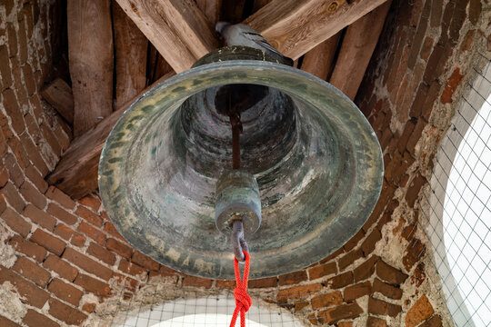 Ancient bronze bell hanging in a traditional brick tower with rope