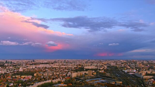 Bucharest, Romania - 15 April 2026: Aerial view of the urban landscape and rooftops under a dramatic pink and purple sunset sky.