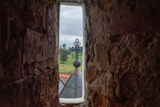 View of a church cross through a narrow stone window embrasure