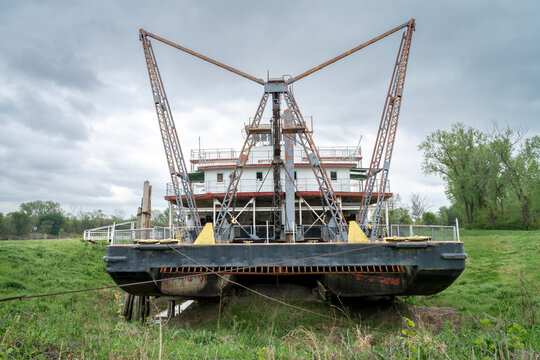 Front of vintage river dredge with a wide suction head and drag shoe in a dry dock on a shore of Missouri RIver