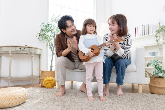 A child enjoys playing a ukulele with their parrent