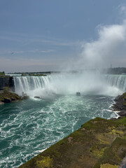 Obraz premium A tour boat loaded with tourists in blue ponchos cruises towards the mist at the base of the Horseshoe Falls in Niagara Falls, Ontario, Canada.