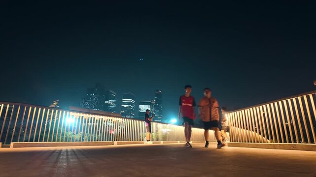 Bangkok, Thailand, 20-04-2026: People walk on illuminated skywalk with city skyline at night hyperlapse, urban park observation deck with pedestrians and cityscape view, Benchakitti park 4k timelapse