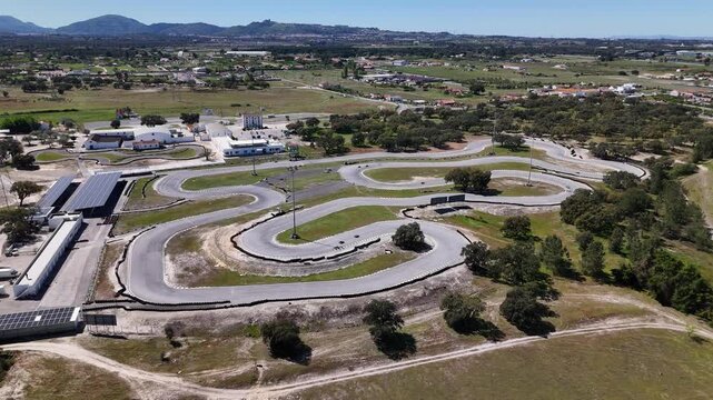Palmela, Portugal - 01 April 2026: Aerial view of KIP - Kartodromo Internacional de Palmela with its winding asphalt track surrounded by green fields and trees under a clear sky.
