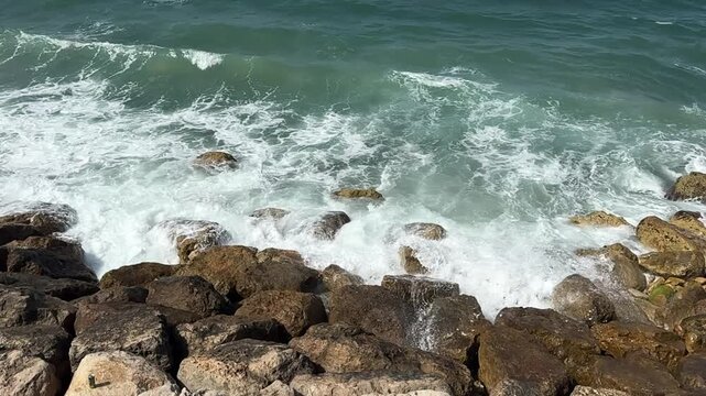 a wave crashes against rocks along the Mediterranean shoreline near Haifa, Israel