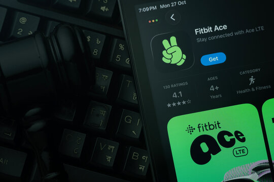 Dhaka, Bangladesh- 28 Oct 2025: An iPad displaying the fitbit ace app against a judge's gavel and dark keyboard background.