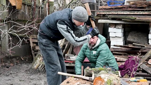 Two Men Chopping Firewood Outdoors in a Rural Backyard During Winter, Manual Labor for Heating Preparation