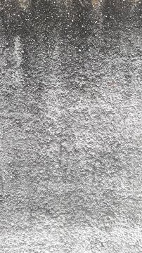 Monochromatic stucco gradients. This close-up captures a weathered, high-contrast concrete wall where dark mineral deposits meet stark, pebble-dashed white finishes. 4k 60fps