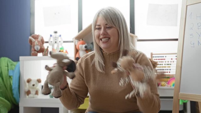 Woman holding plush hand puppets and animating them while smiling in a preschool classroom building; playful learning joy.