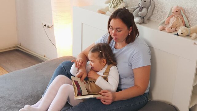 Parent reads to her daughter during a relaxed moment at home. Encouraging preschool growth through books. Top view, mid shot