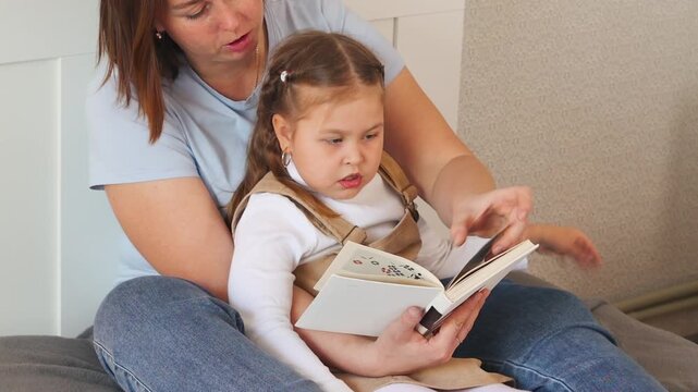 Little girl listens to her mother reading a story. Calm environment for early education and language growth. Mid shot