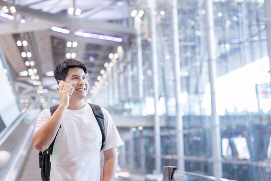 Man stands at airport with phone in hand looking around at terminal