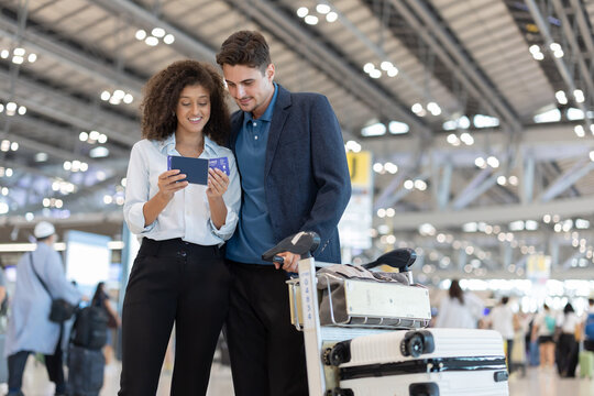 Couple checks travel details on their ticket at the airport before their flight