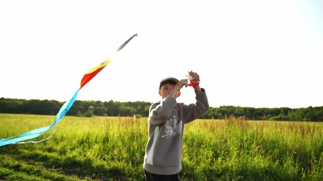 Boy laughs, running with colorful kite in golden sun. He grips string, eyes bright with joy and freedom. Field stretches wide, trees form soft backdrop