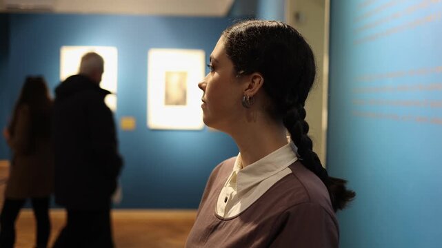 History and culture. Portrait of young intelligent Caucasian woman watching art gallery. Visiting excursion in art gallery. Concept of educational tourism