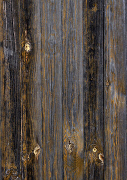 Aged dark wood planks with yellow paint splatters and knots. Rustic background.