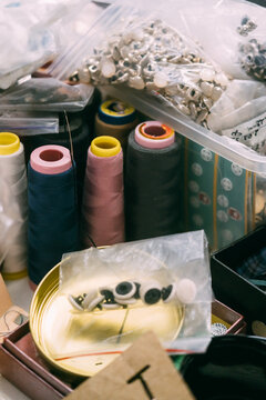 Sewing supplies. Tailor accessories. Colorful thread spools placed with storage box buttons for professional garment manufacturing.