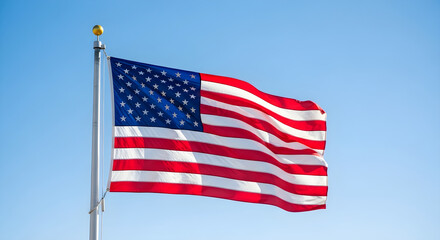 Obraz premium American flag waving on flagpole against a clear blue-sky background