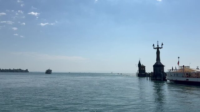 Fast passenger ferry arrives at Konstanz ferry terminal. Imperia statue at Lake Constance harbour. Panoramic view of Konstanz lake. Motion of waves. Konstanz, Germany 