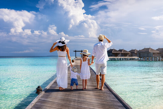 A elegant family of four enjoys their tropical vacations in the Maldives islands as a concept for travel and vacations