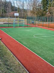 Fototapeta premium Empty multi-sport playground with artificial turf and basketball hoop in the park.