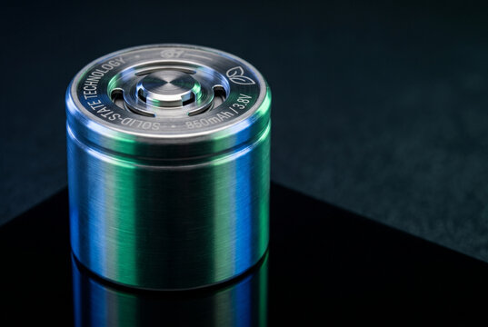 Macro close up of next generation solid-state battery cell with brushed metal texture on dark reflective background