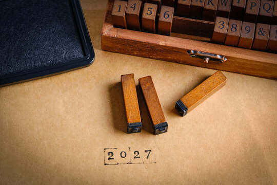 Warm color photo wooden stamp blocks and box. The year 2027 is stamped on aged paper.