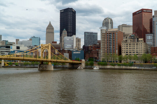 Pittsburgh Skyline with iconic Roberto Clemente Bridge over Allegheny River on a cloudy day, featuring downtown buildings like UPMC and K&L Gates.