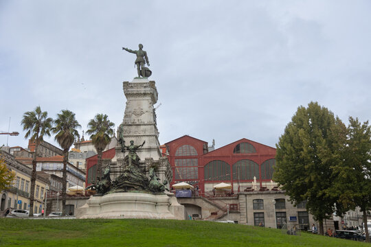 A historic monument of Dom Pedro IV stands prominently in Porto, Portugal, set against the iconic Ferreira Borges Market, blending cultural heritage with urban architecture under a cloudy sky.