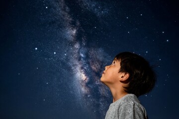 Fototapeta premium Young boy gazing at milky way in clear night sky outdoors