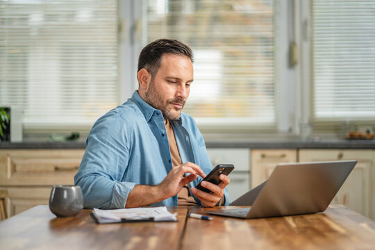 Man working from home using smart phone and laptop