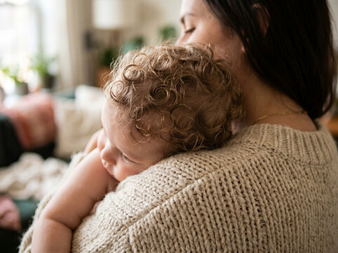 Close up of a mother nuzzling her babys cheek in a bright room