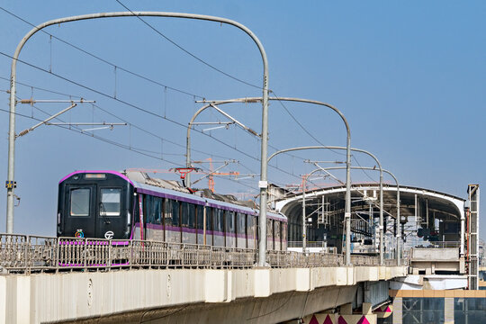 Close up image of Fresh, new rake of Pune metro train exits metro station and runs on overhead track .