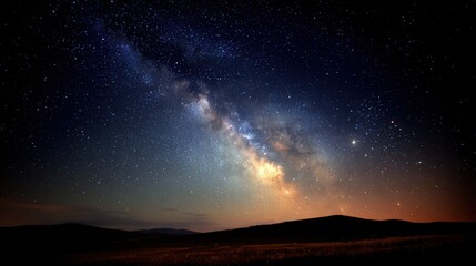 Fototapeta premium Milky Way galaxy stretches across the dark night sky above a silhouette of rolling hills.