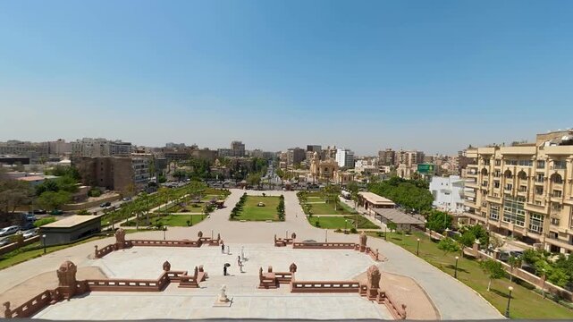 CAIRO, EGYPT - APRIL 25, 2026: Time-lapse high angle view from the historic Baron Empain Palace, overlooking the front gardens, visitors, and the dense urban traffic on the bustling Salah Salem Road i